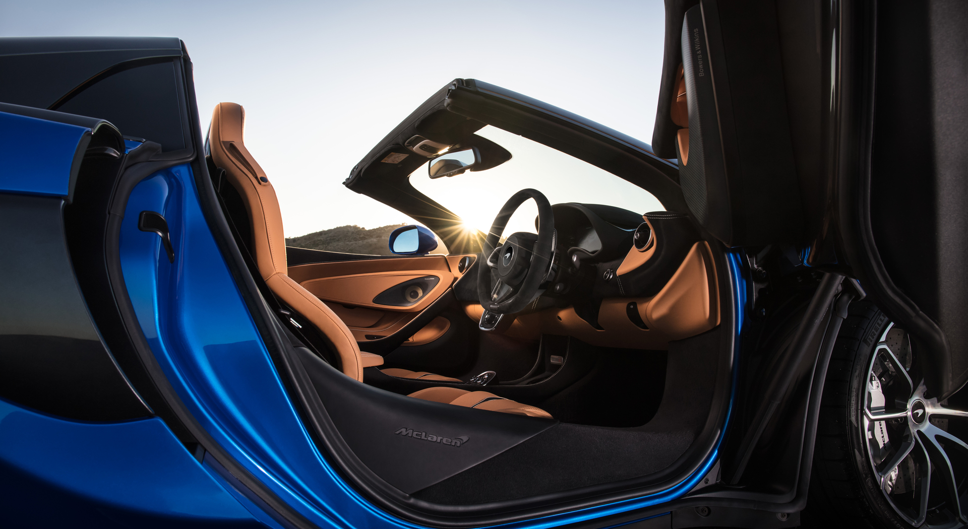 Interior of a blue McLaren 570S Spider, photographed through the open dihedral drivers side door.