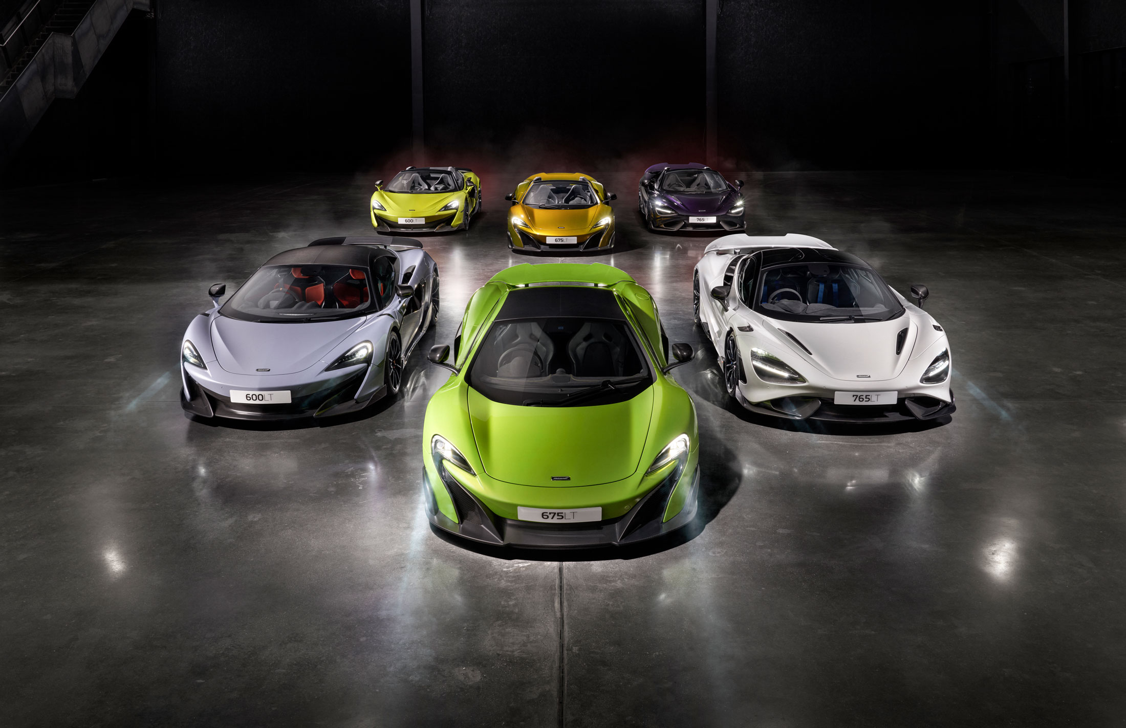 McLaren LT supercar lineup arranged in a V formation, featuring 600LT, 675LT, and 765LT models in bold colors, showcasing aerodynamics.