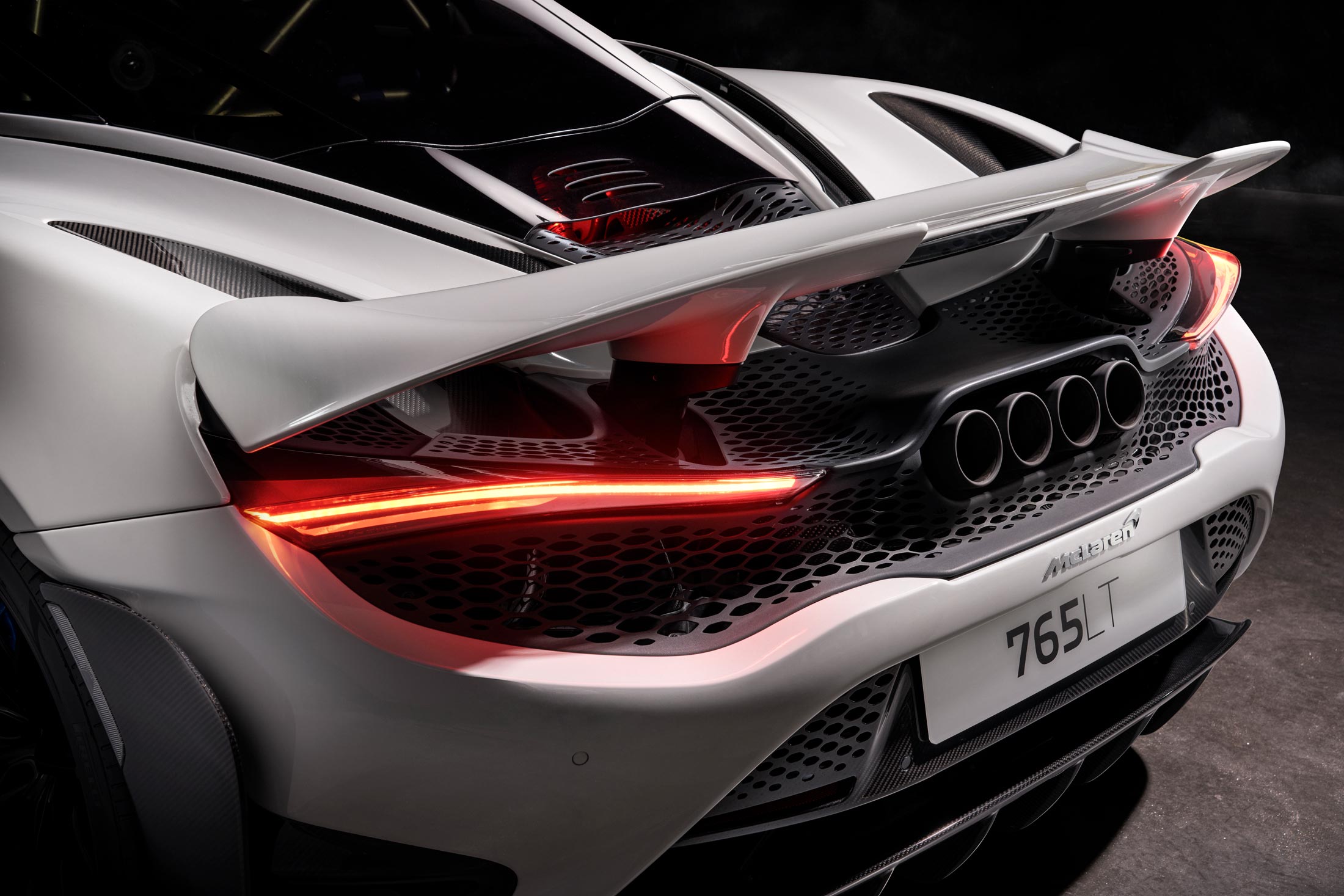 McLaren 765LT rear view in white, featuring an active rear wing, quad exhaust system and aggressive track styling