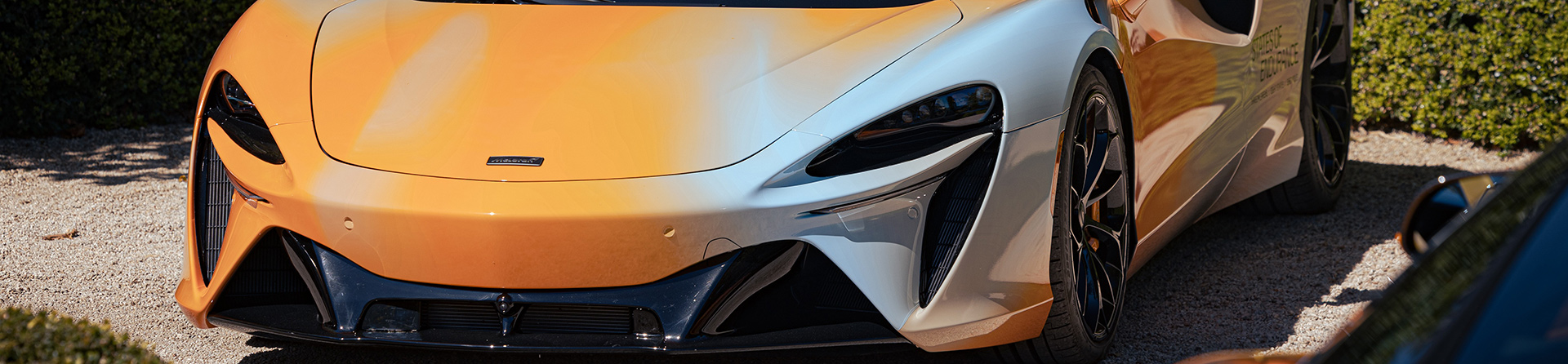 Close-up front view of a McLaren Artura supercar featuring the bespoke orange and white 'States of Endurance' journey livery.