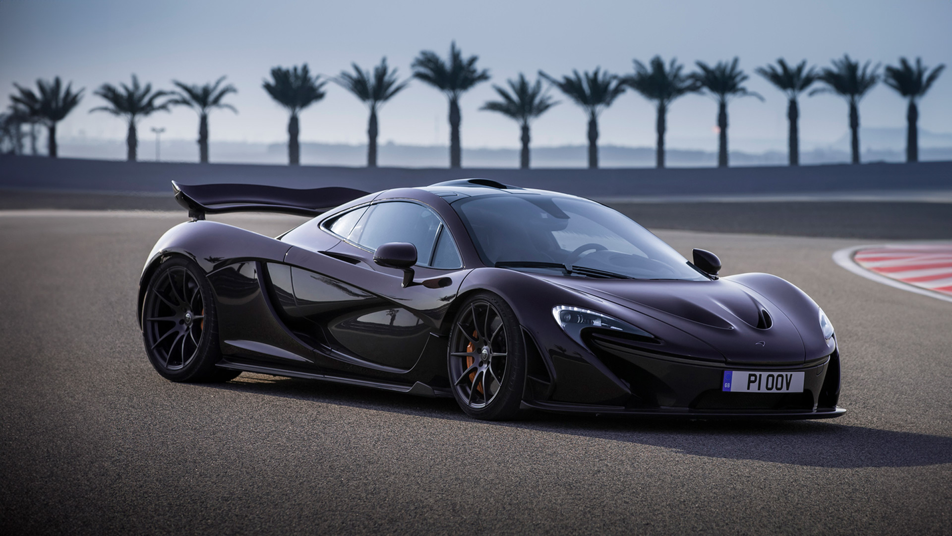 A dark purple McLaren P1 with active aerodynamics parked on a circuit, showcasing its design and large rear wing.