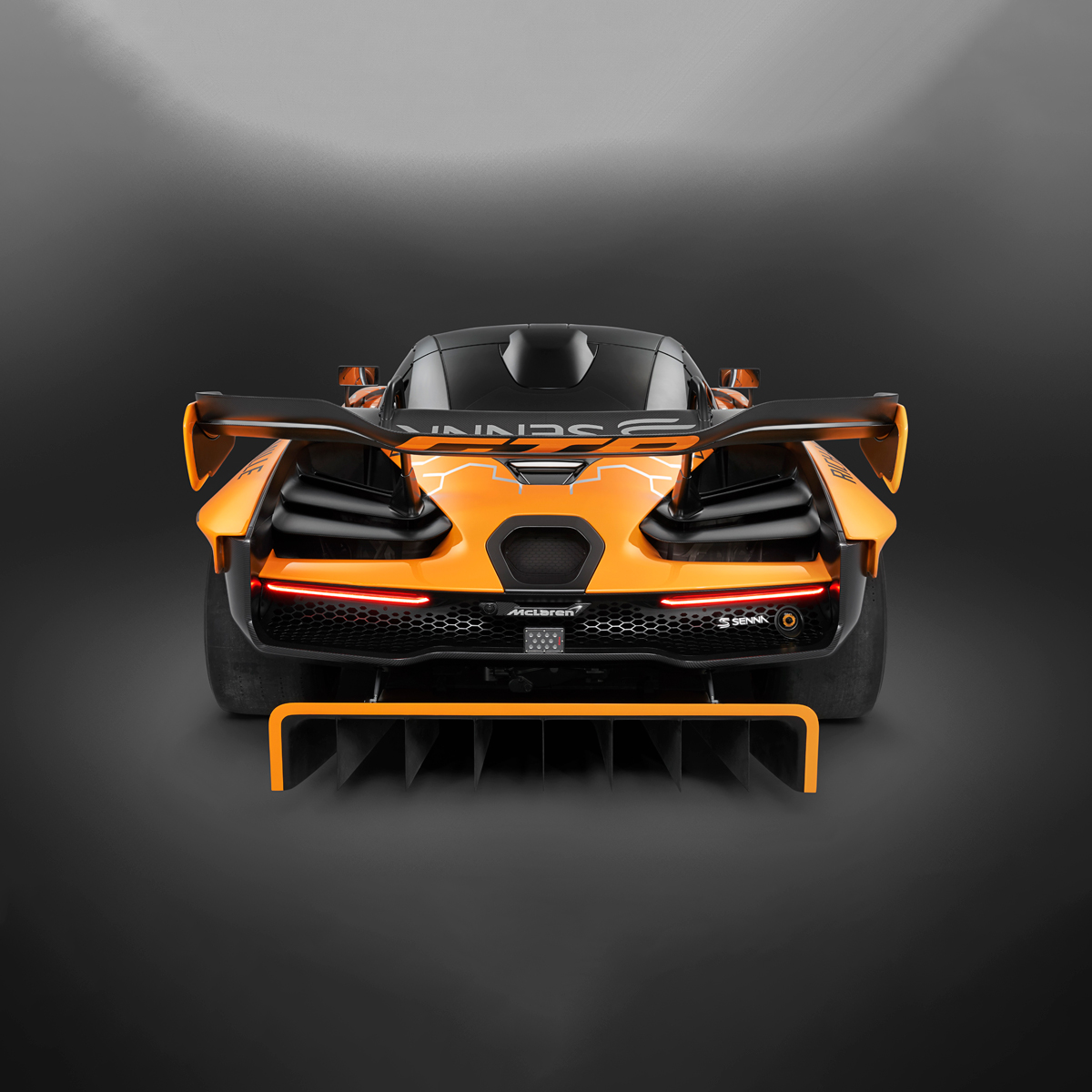 Dead rear view of the McLaren Senna GTR Concept car, showcasing the spoiler and other aerodynamic mechanisms. Photographed in a dark studio environment.