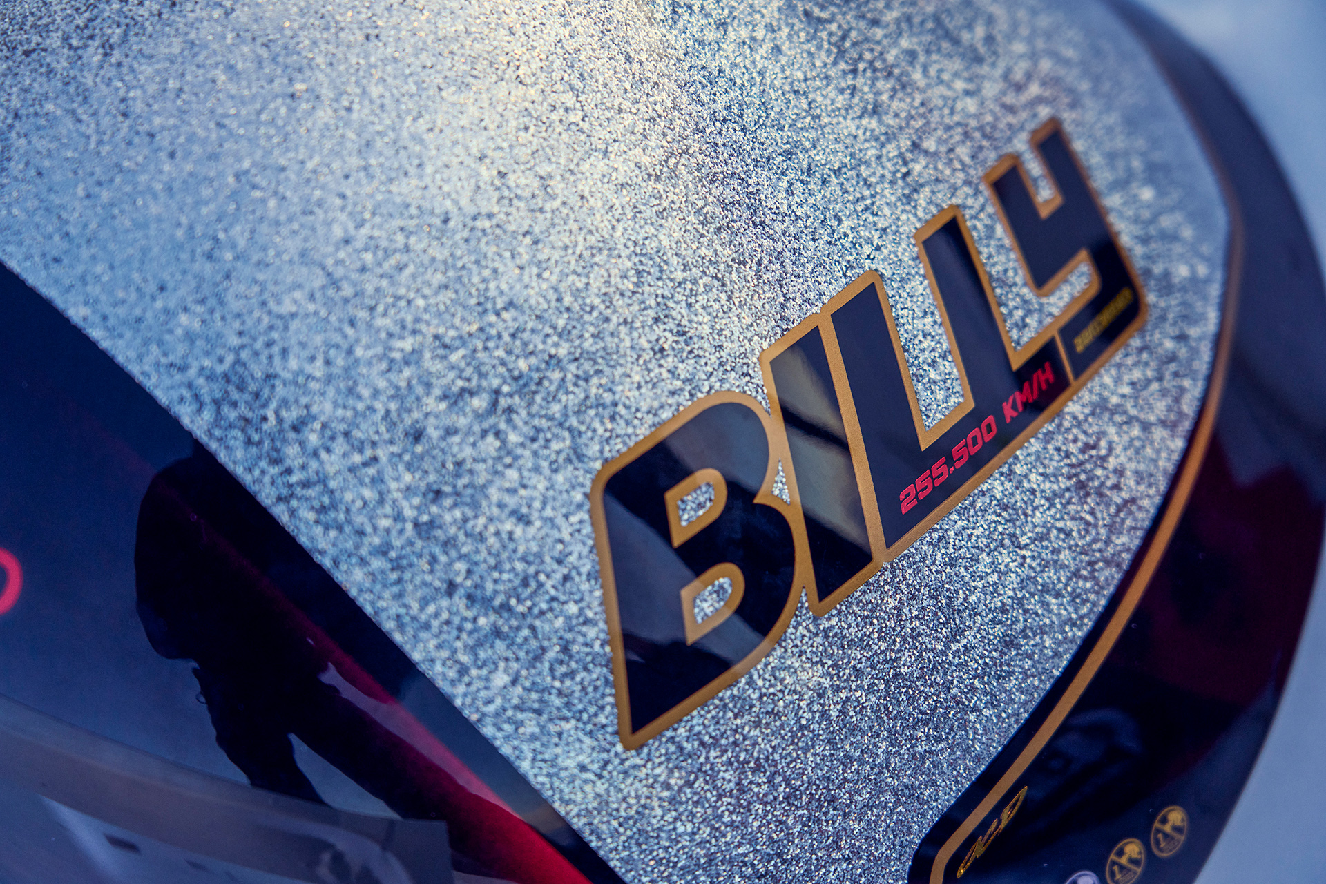 Close up detail of a glittery ski hemet with Billy's name and the speed 255.500 KM/H written on it.