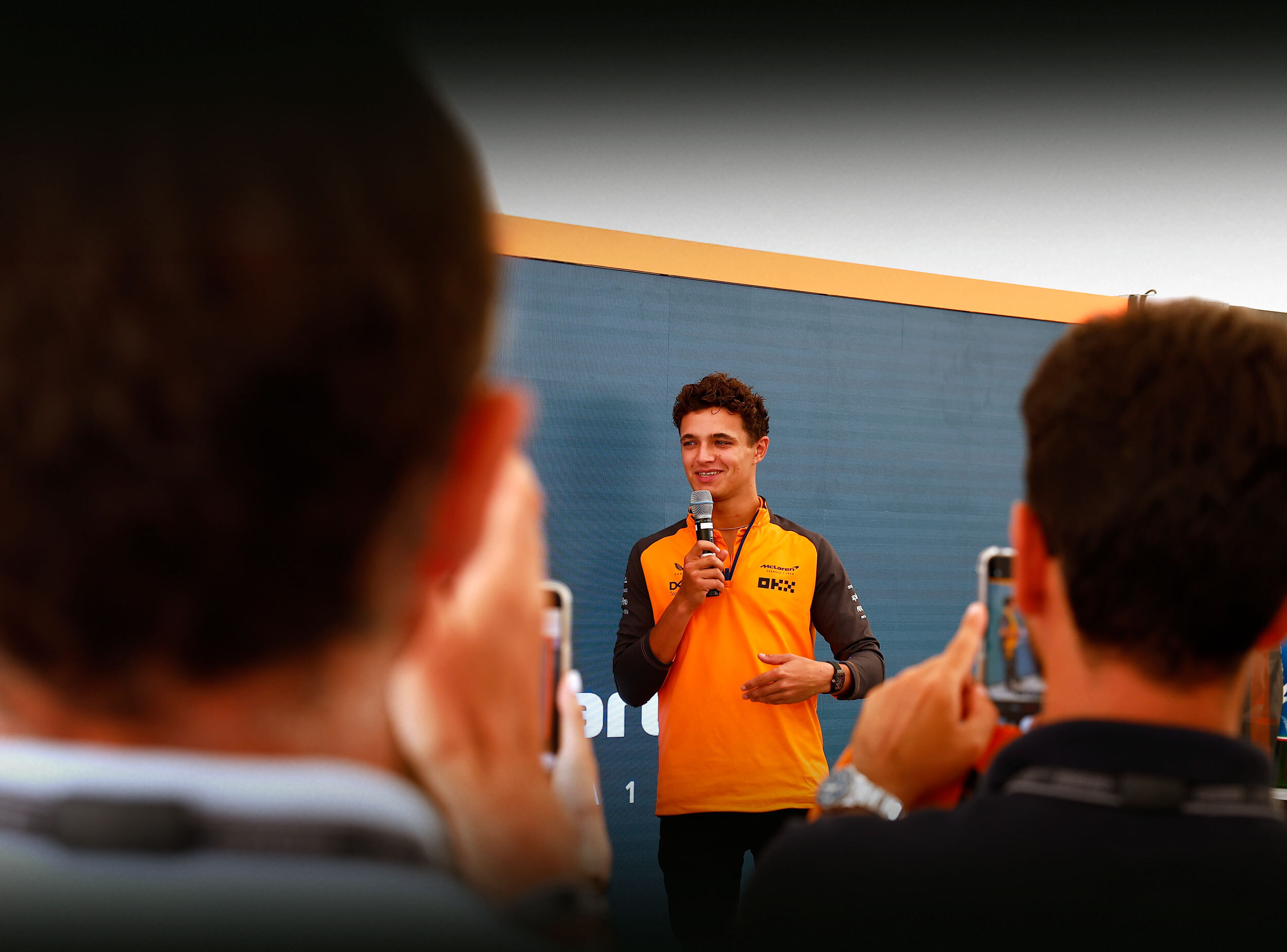 Lando Norris giving a speech at an event wearing McLaren uniform.