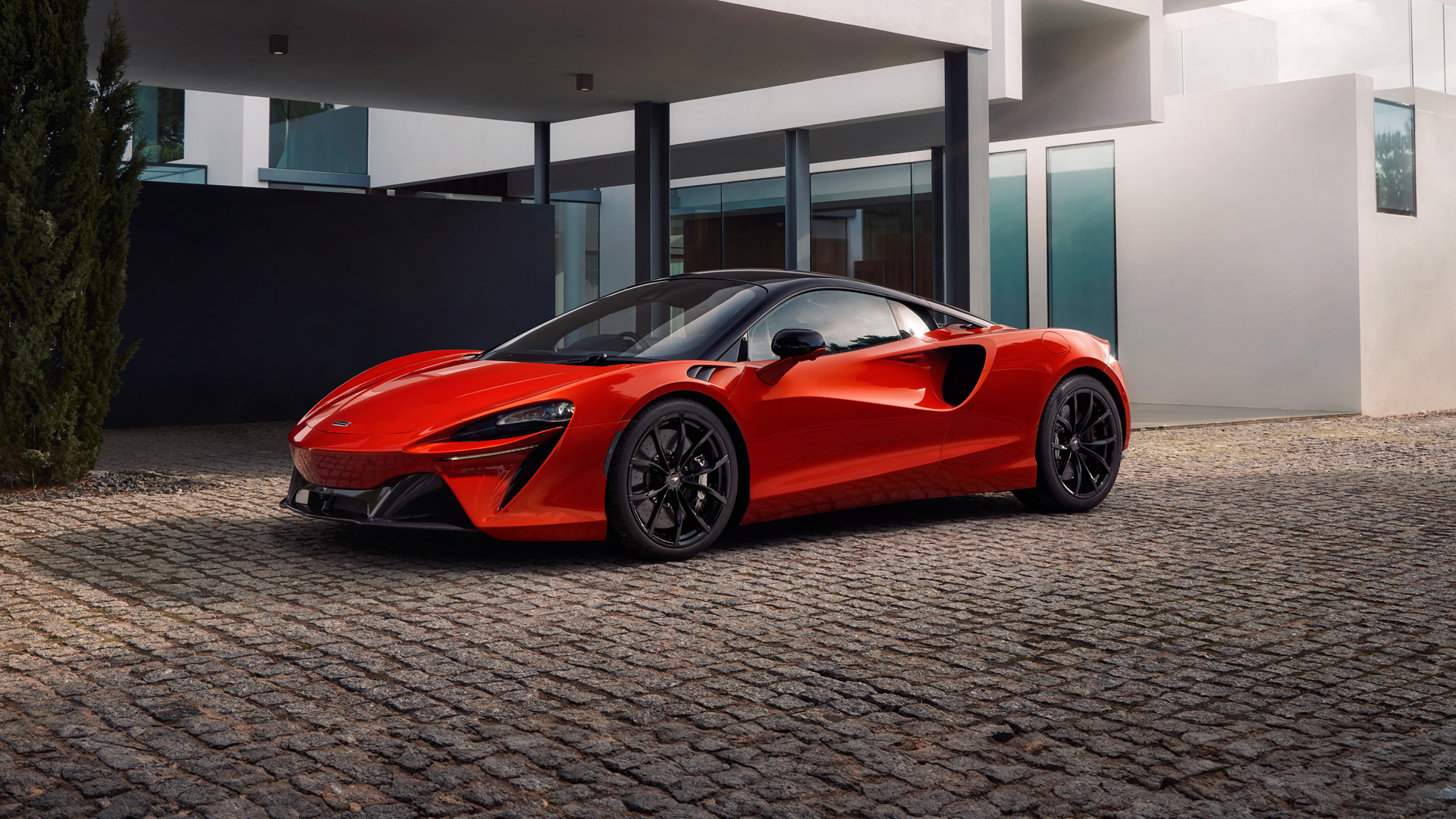 Red Mclaren parked outside of a modern house.