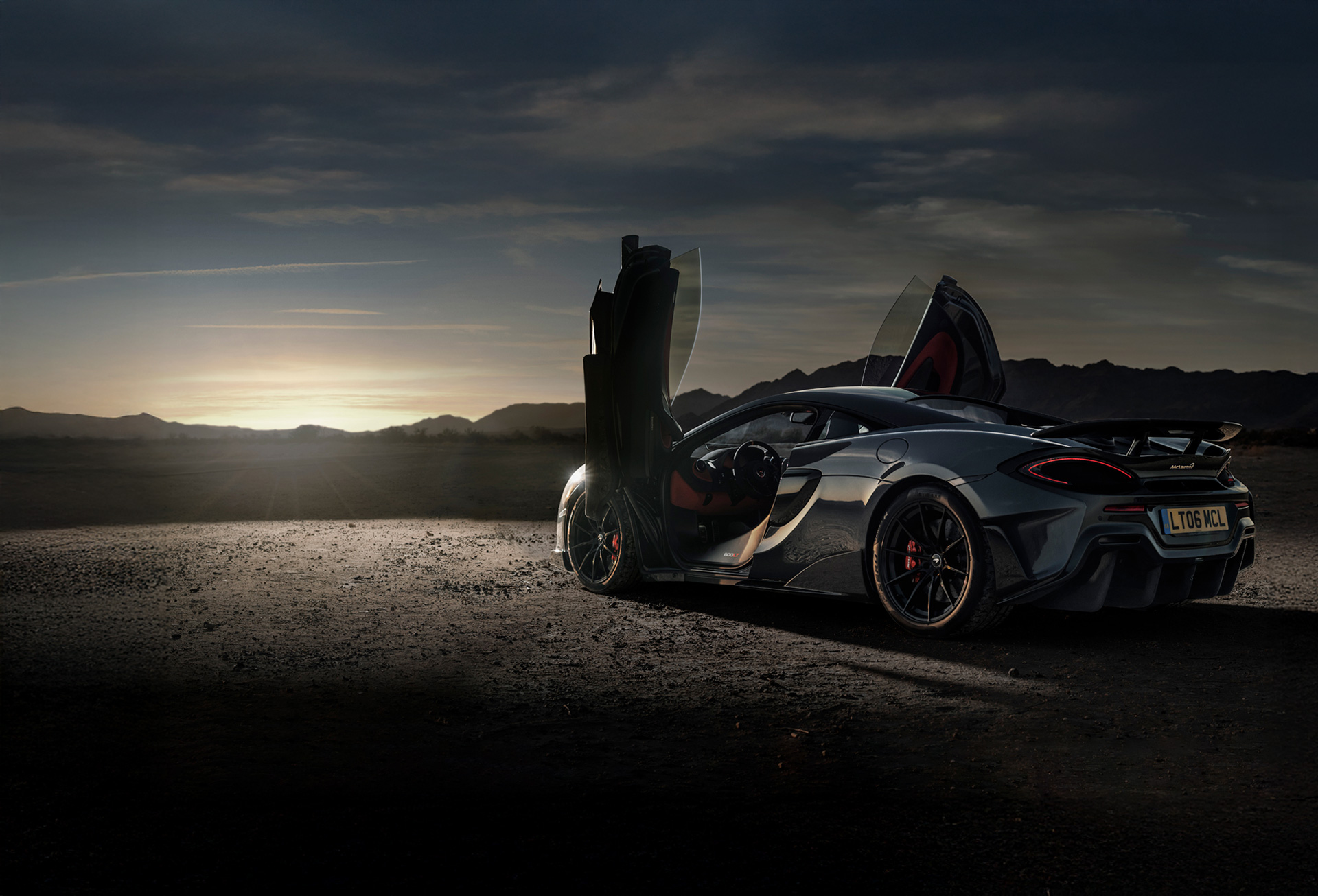 Grey McLaren 600LT parked on a cliff edge with dihedral doors open.