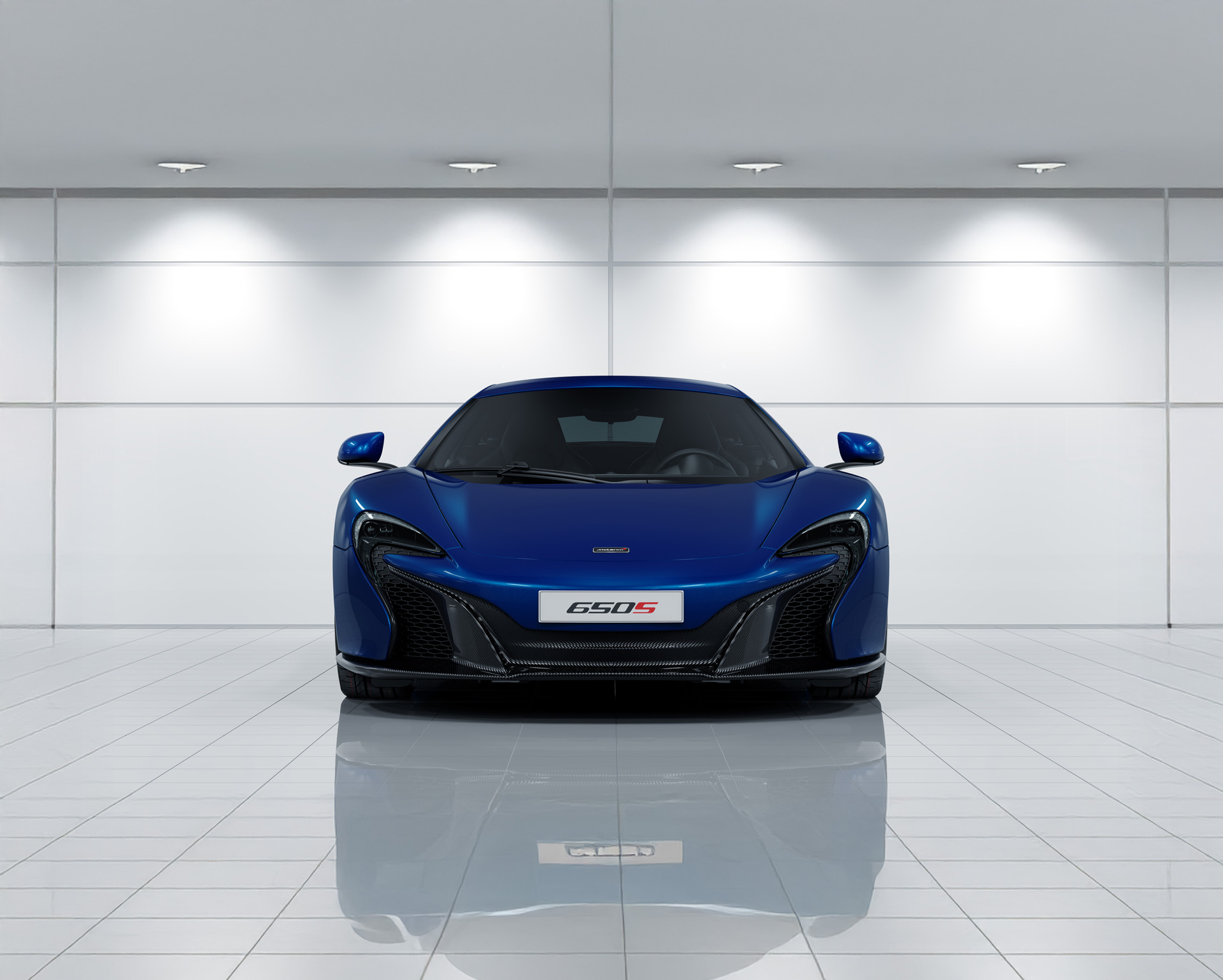 Front view of a blue McLaren 650S in a clean, bright environment.