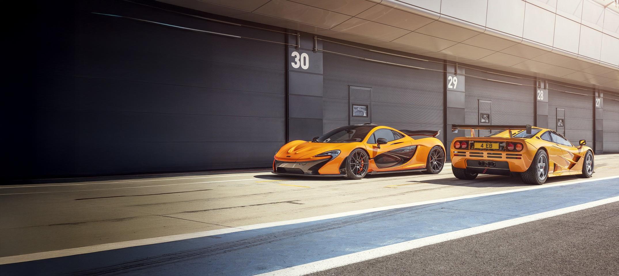 Two orange McLarens parked in a racing pits