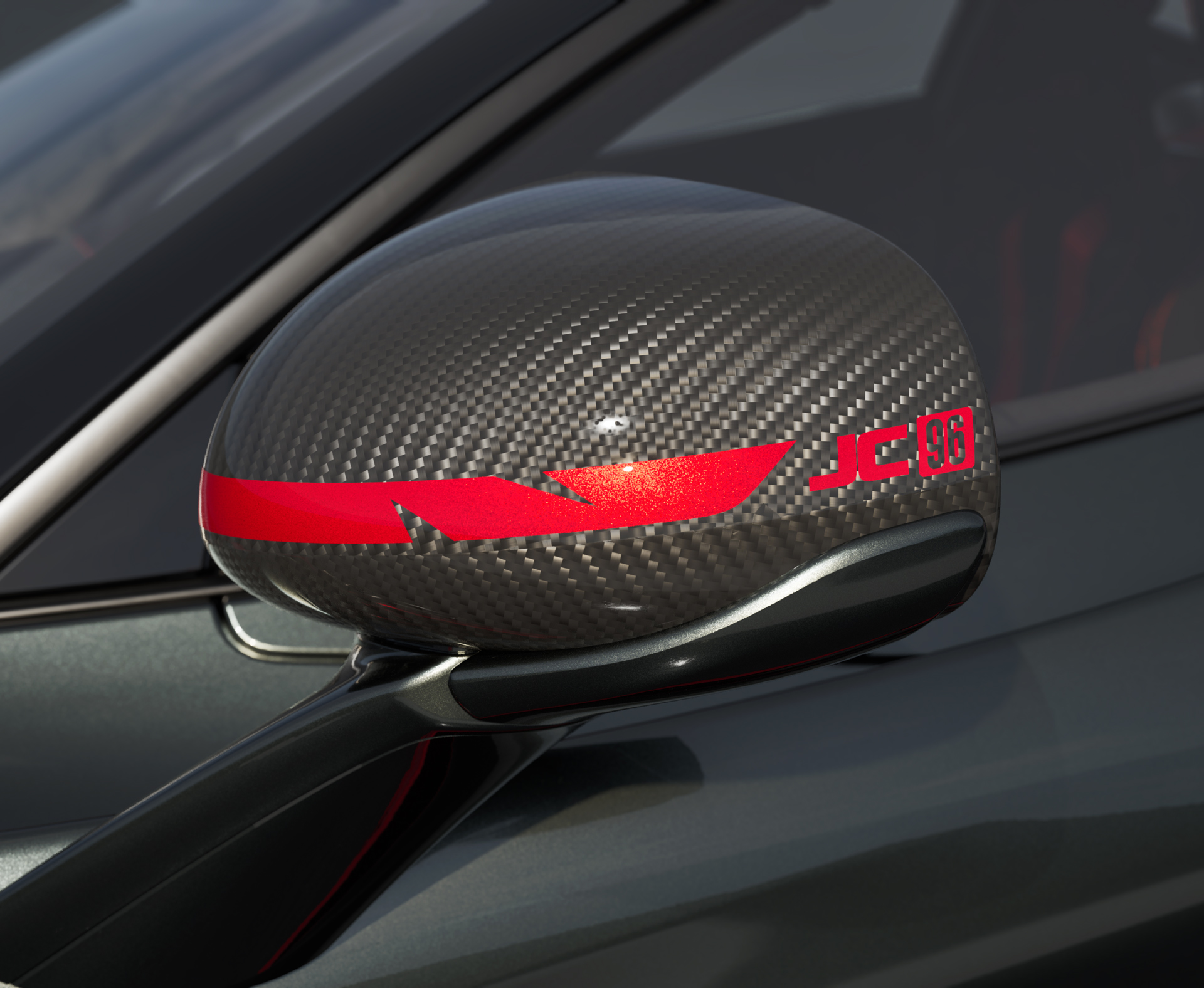 Close-up of the McLaren 750S JC96's carbon fiber wing mirror with a red stripe and "JC96" logo.