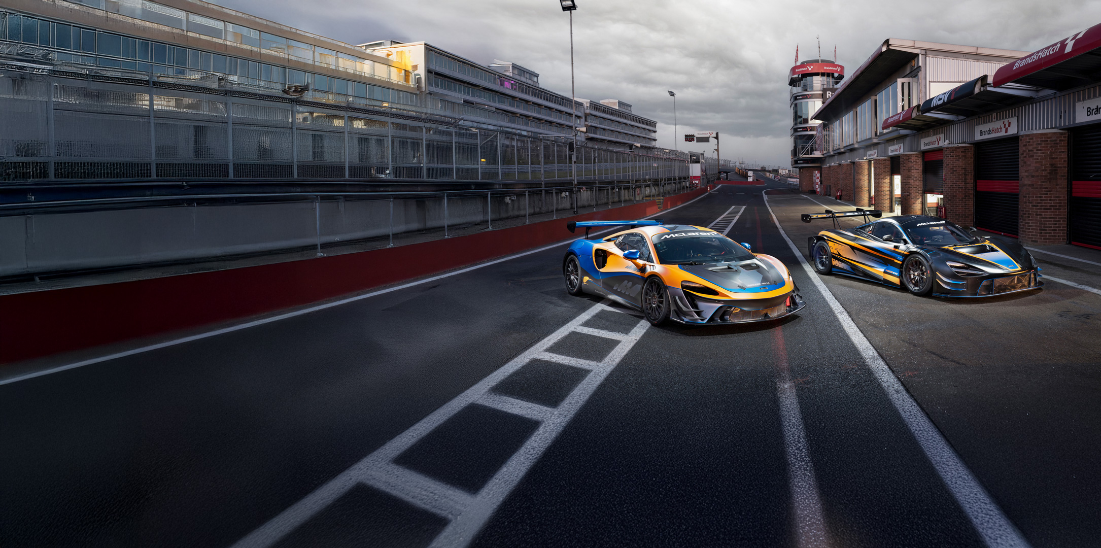 A McLaren Artura Trophy / GT4 (left) and a McLaren 720S GT3 Evo parked on a race track.