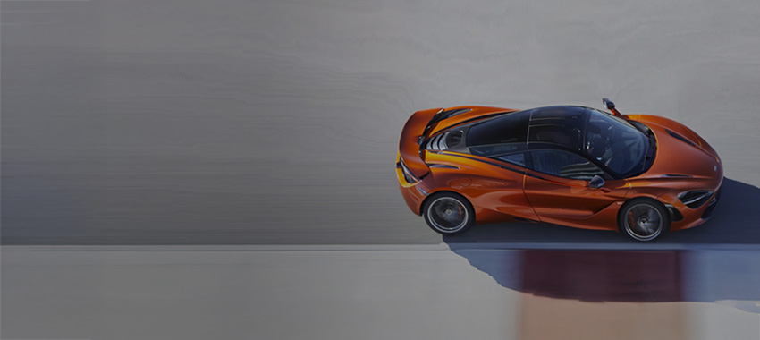 Orange McLaren 750S driving at speed down a tack.