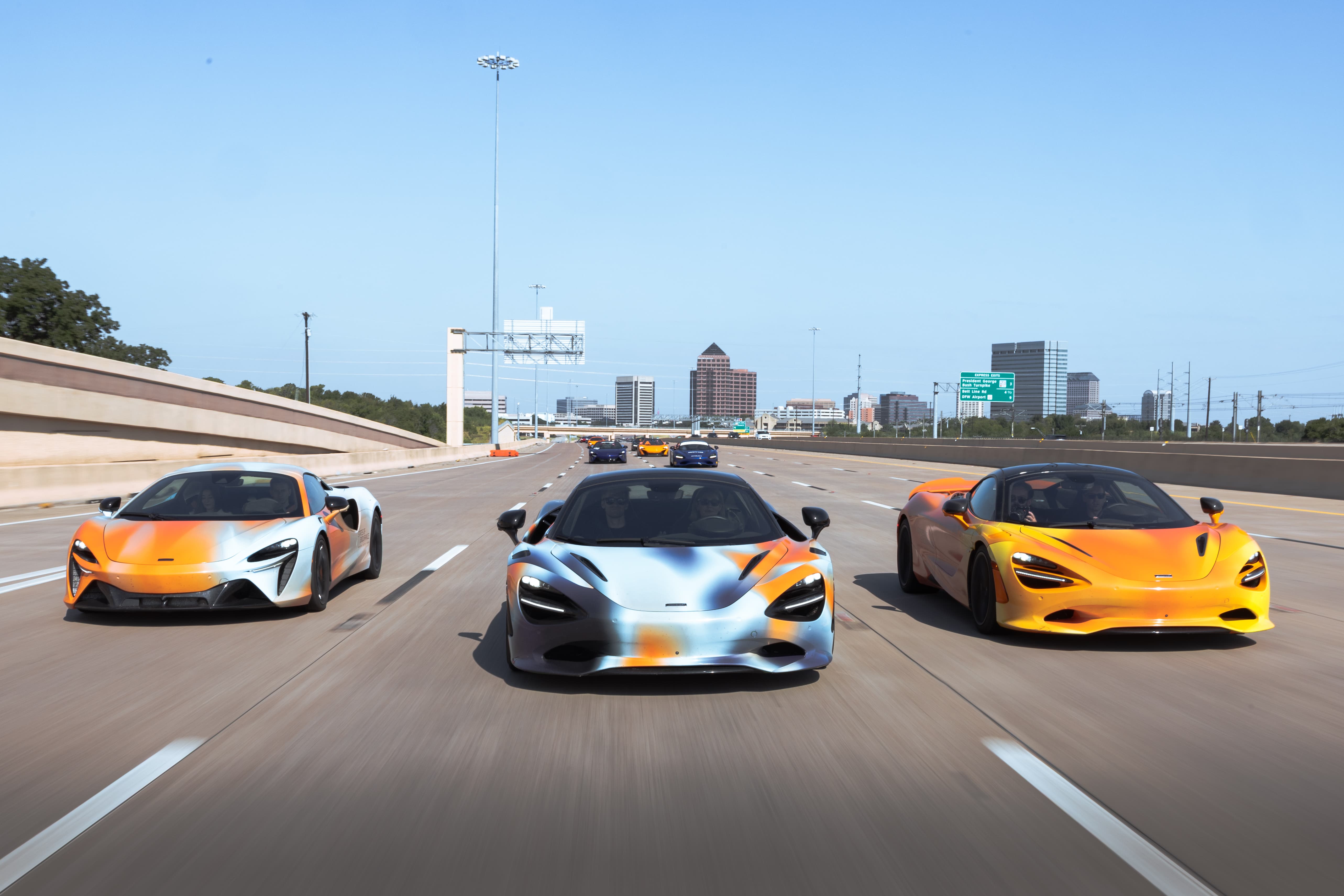 The States of Endurance convoy driving side by side across 3 lanes down the highway, followed by the customer convoy behind them. A scene from Day 7 of the 'McLaren States of Endurance' road trip.