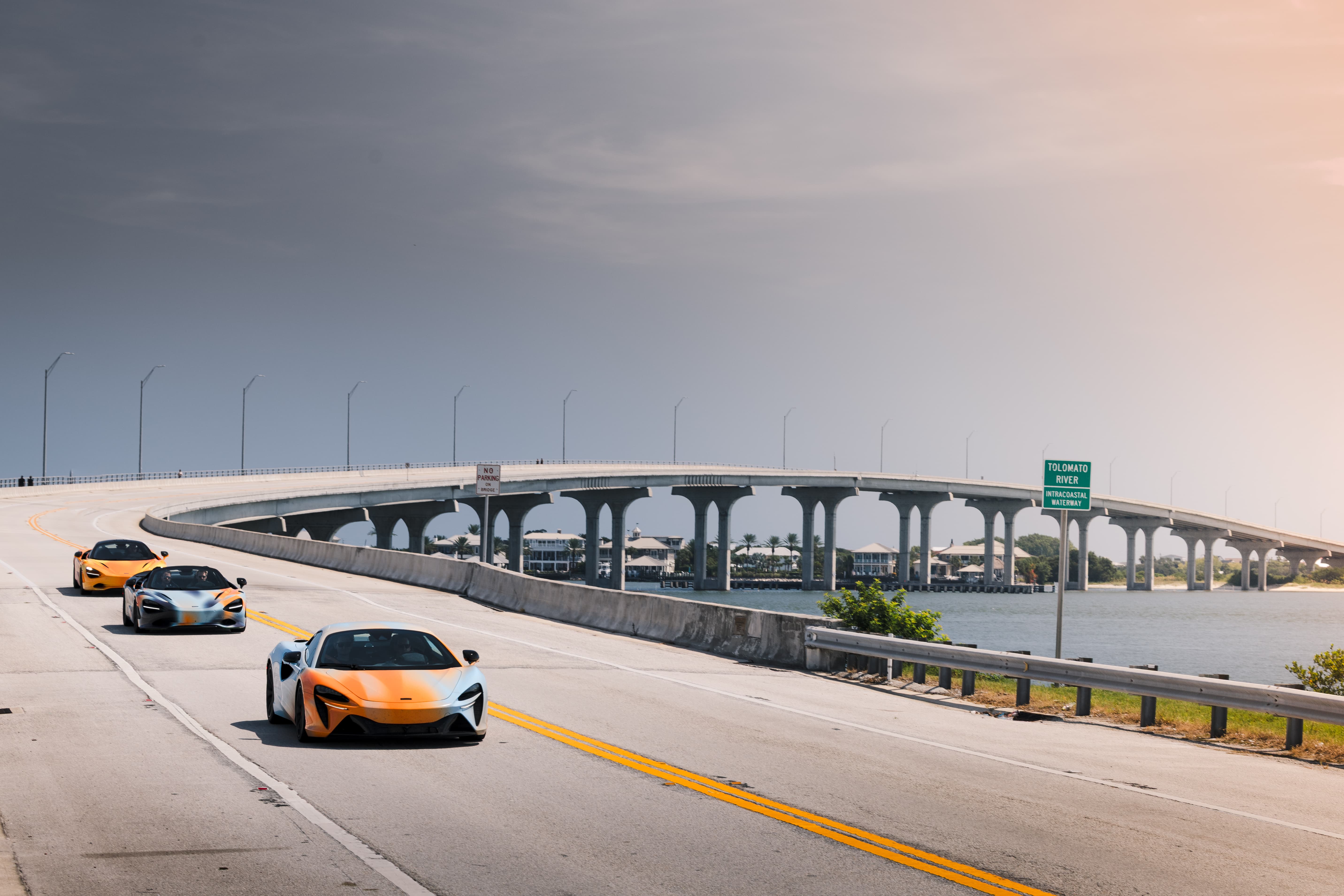 The State of Endurance McLaren cars driving over a tall curved bridge. A scene from Day 10 of the 'McLaren States of Endurance' road trip. 