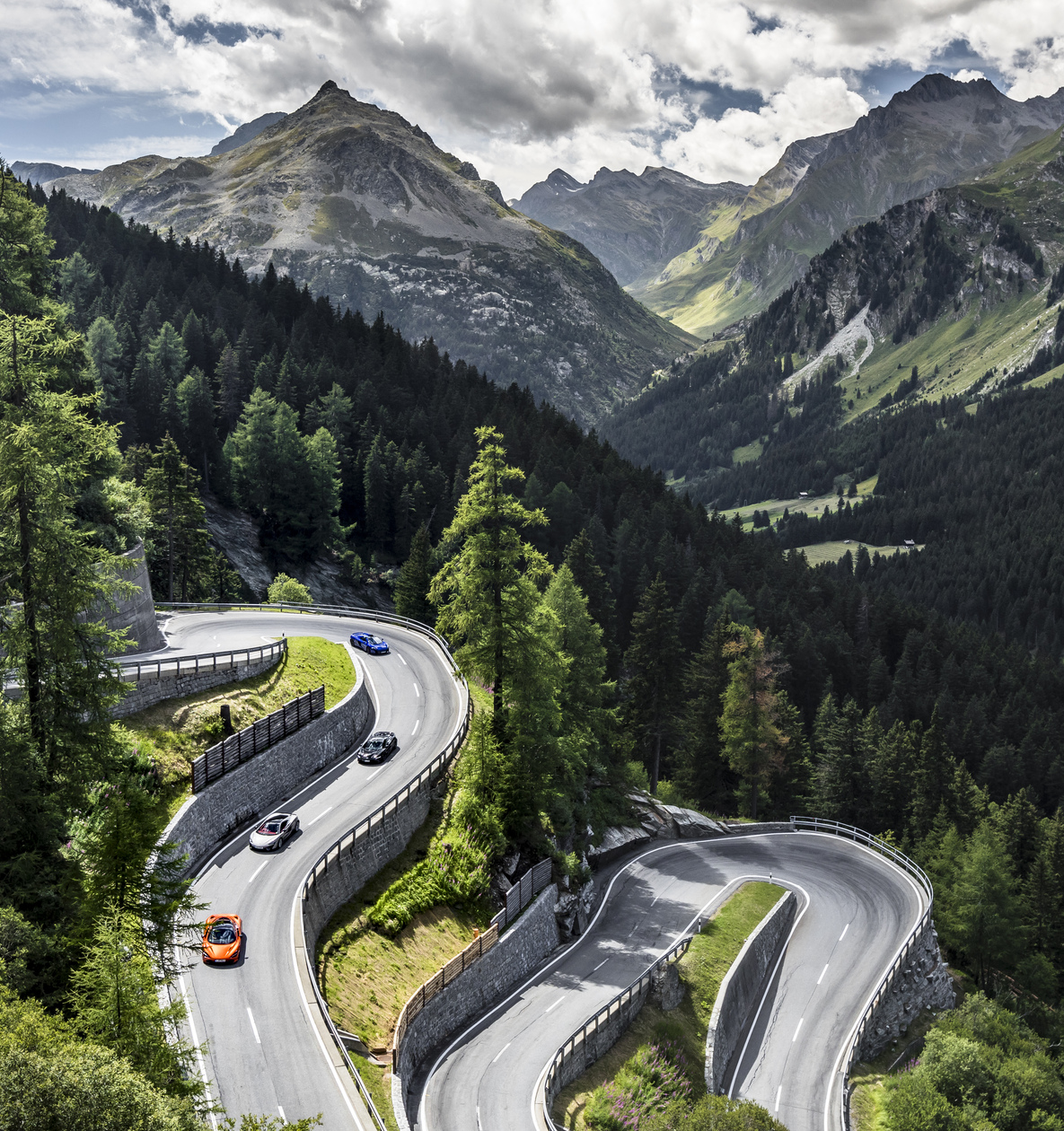 McLaren cars driving down a winding mountain road.