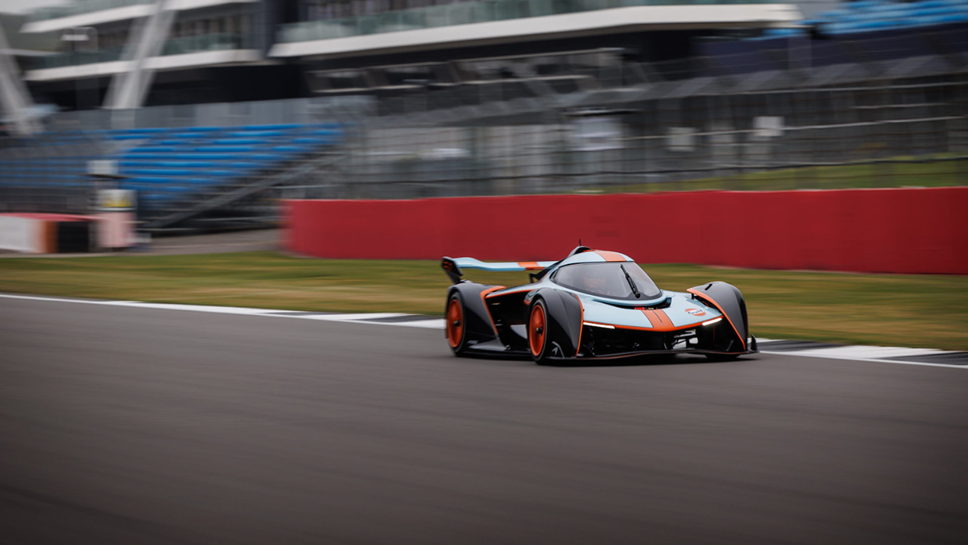 A McLaren Solus GT track car with its Gulf-inspired livery speeding on the circuit, highlighting the high-performance McLaren experience.