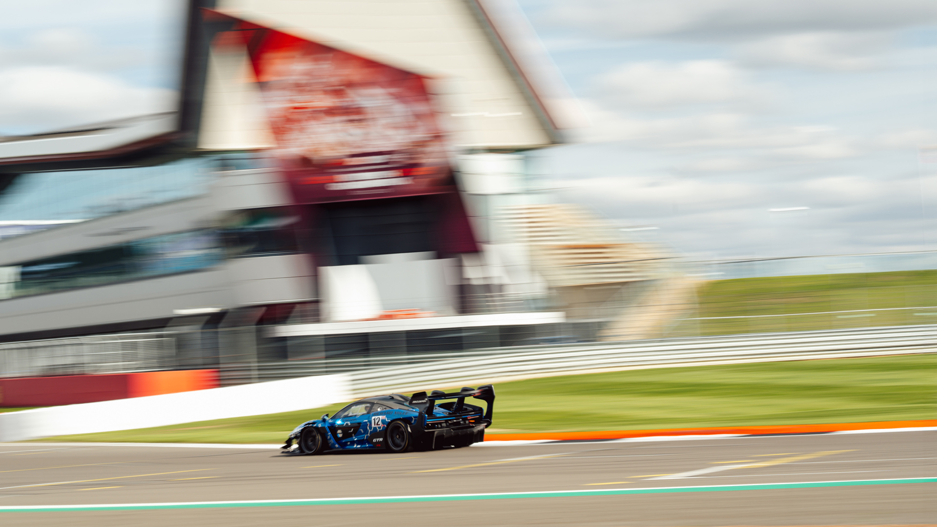 The McLaren Senna GTR driving at speed along the Silverstone track with motion blur to emphasise the speed.