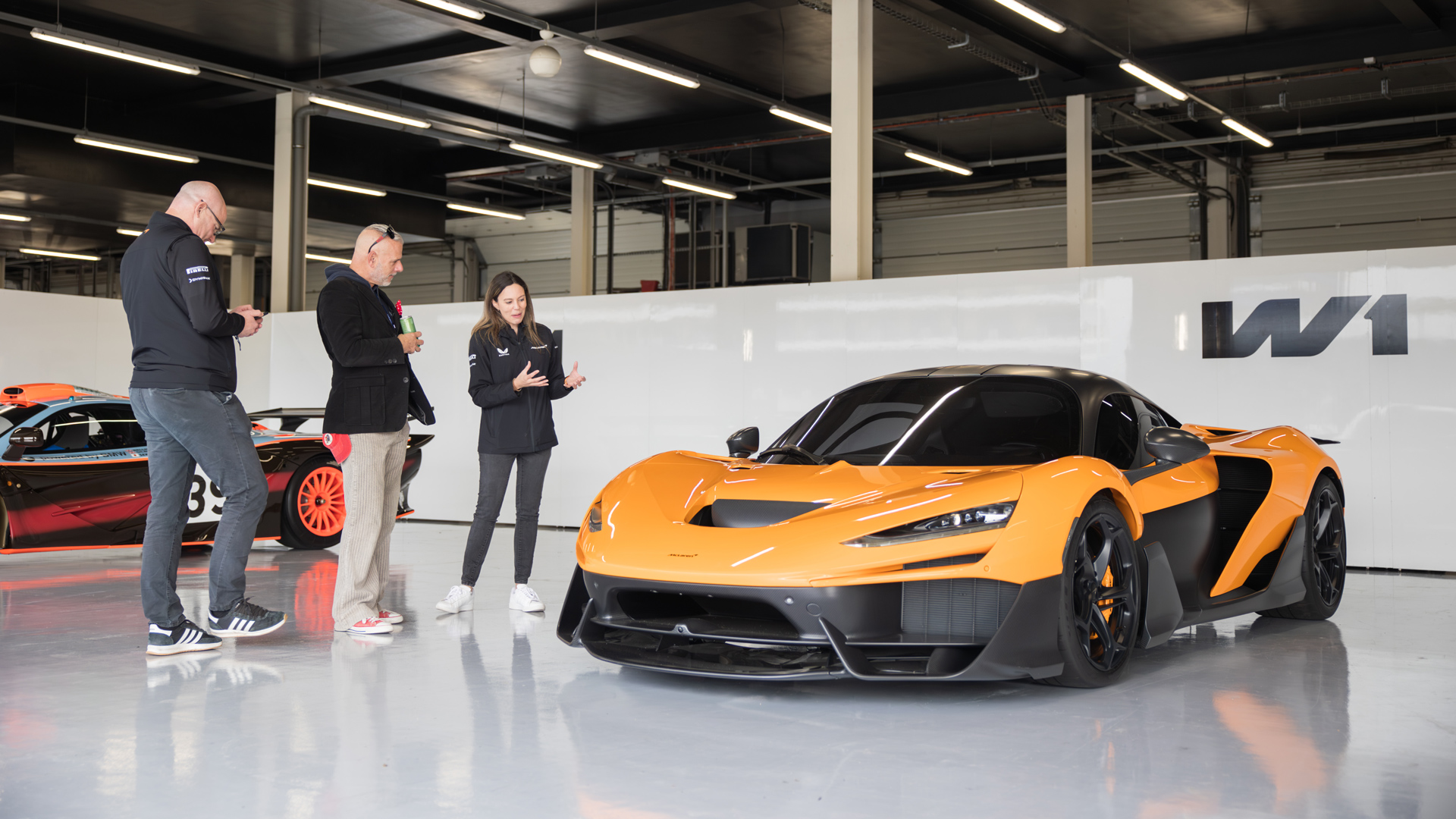Two McLaren staff members presenting the McLaren W1 to a participant.