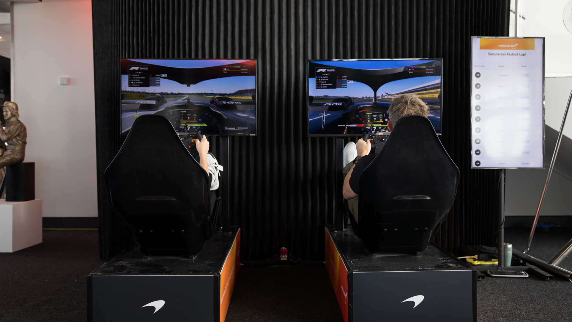 Two Silverstone participants using a Formula 1 driving simulator.