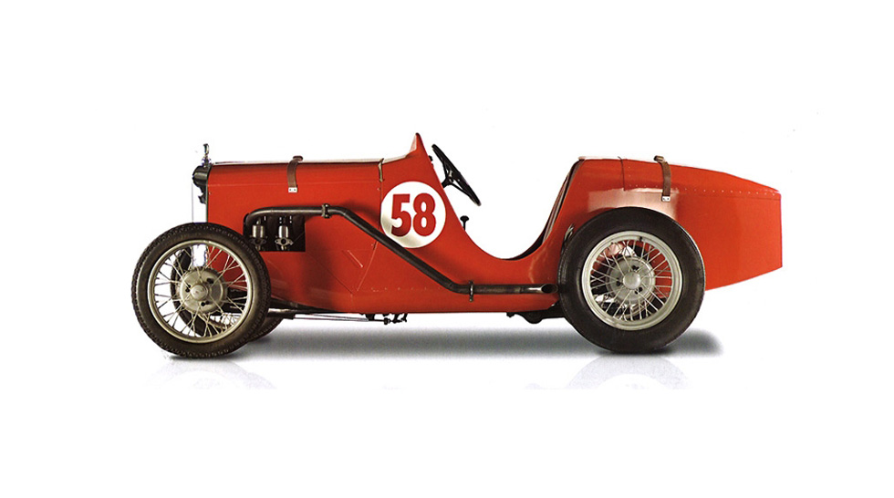 Side view of a red McLaren Austin Ulster, with the number 58 on the side of the body, photographed on a red background.