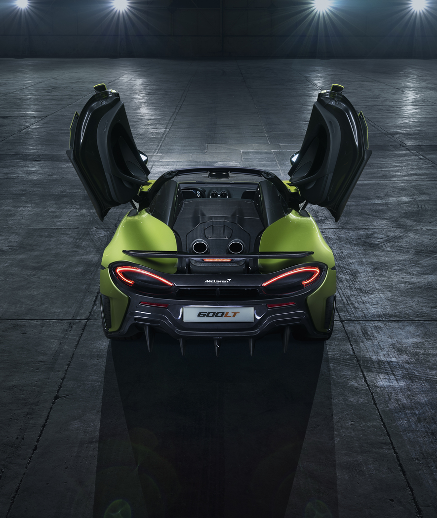 The rear of the McLaren 600LT Spider, with its top-exit exhausts and iconic dihedral doors raised in a dark studio.