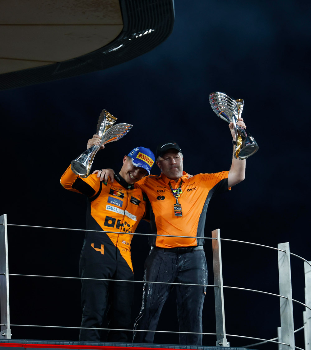 Lando Norris and Zak Brown - arms around each other, holding up the Hawthorn Memorial Trophy and the Sir Malcolm Campbell Trophy for their achievements in the 2024 Formula 1 season. 