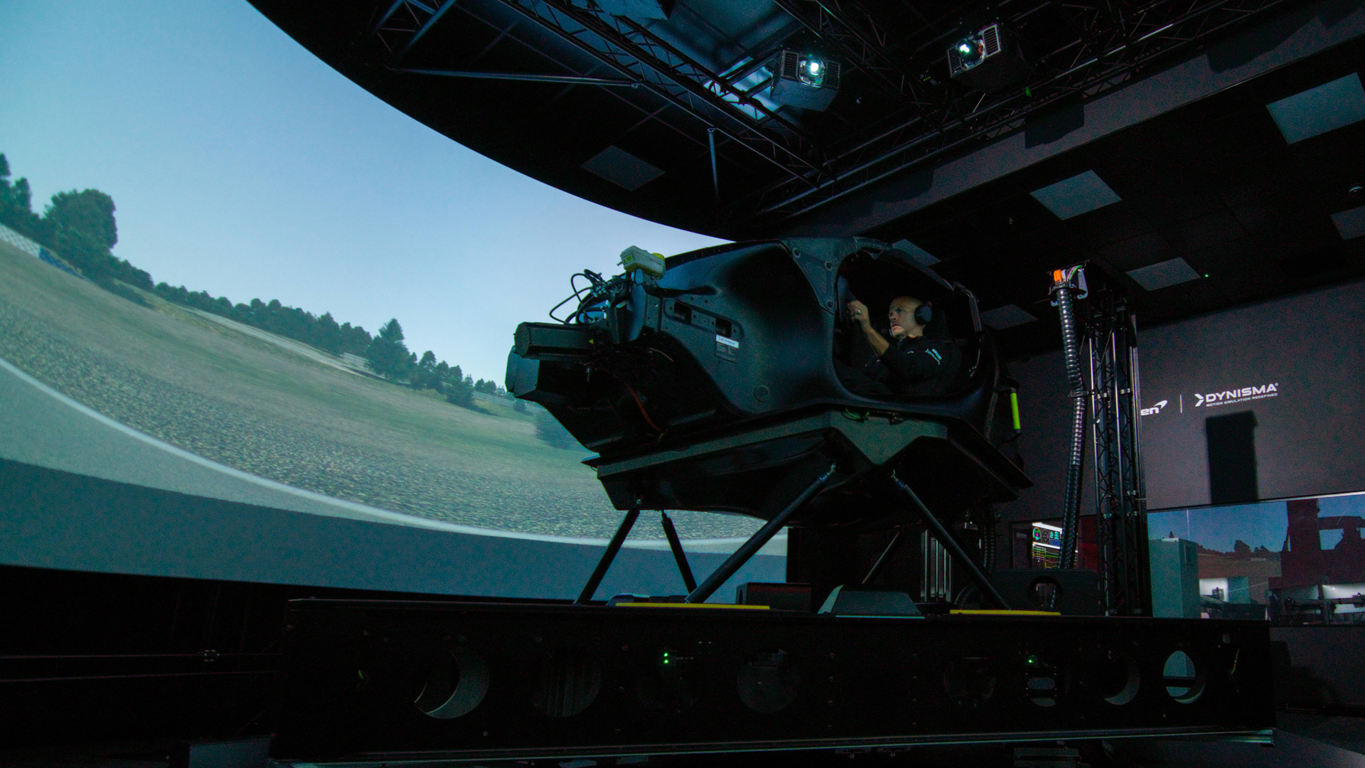 McLaren driver testing in a high-fidelity Dynisma motion simulator, highlighting the advanced technology partnership for dynamic vehicle development.