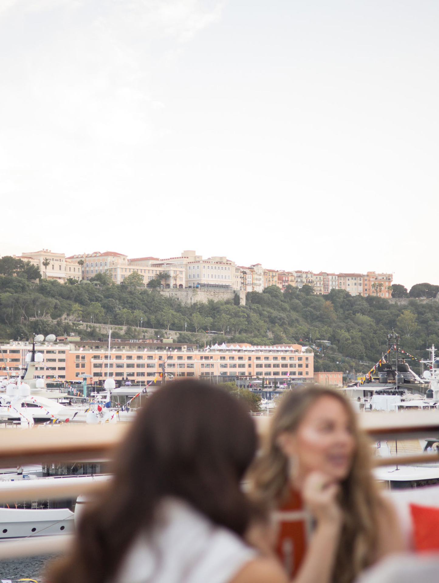 Guests enjoying a luxurious harbor view from a yacht or balcony, emphasizing the comprehensive full package experience of the McLaren Monaco Grand Prix event.
