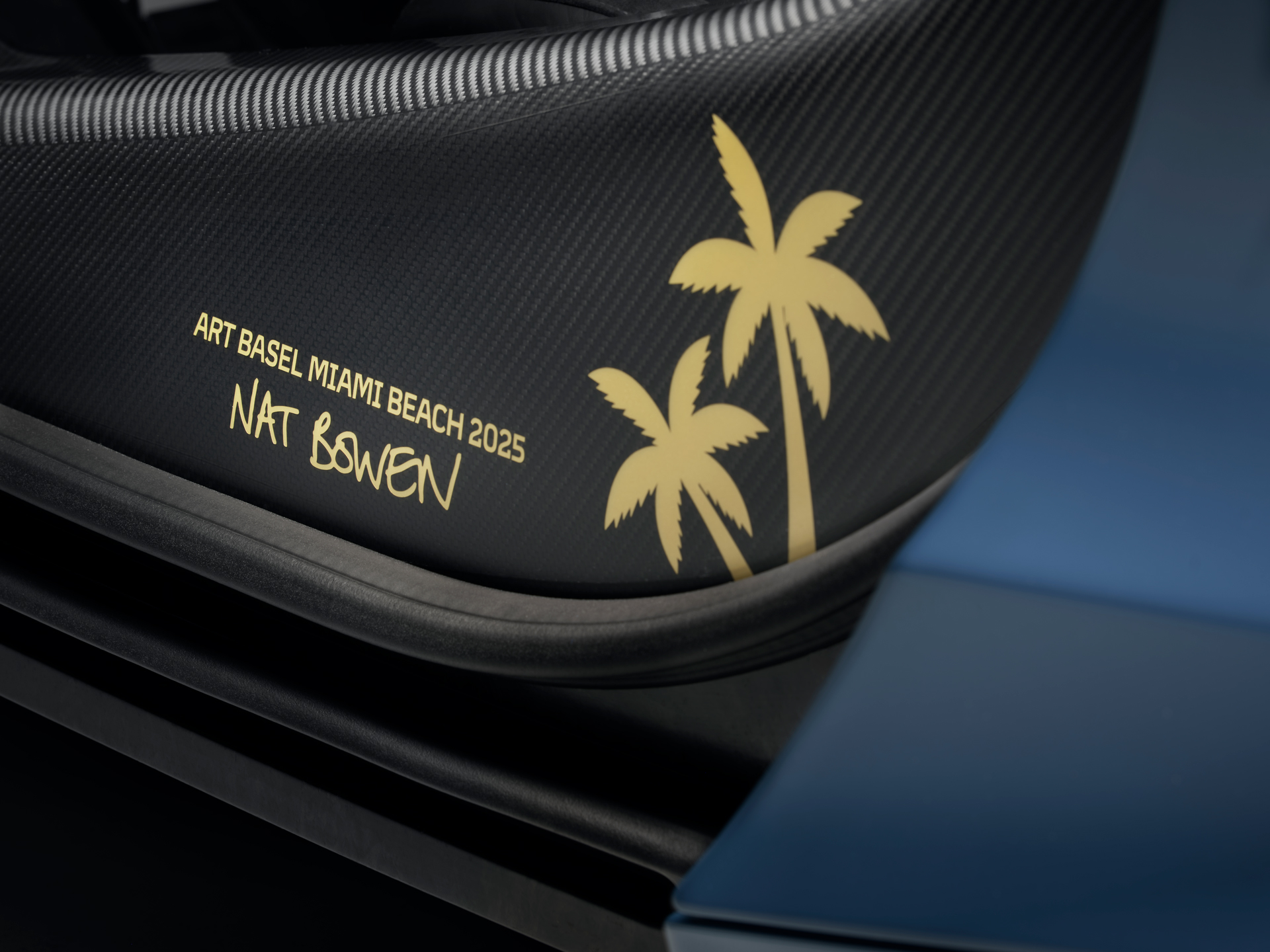 A gold sticker on the microfiber interior of the The Project Chromology 750s by MSO and Nat Bowen. The sticker shows two palm trees next to text which reads 'ART BASEL MIAMI BEACH 2025, NAT BOWEN'.
