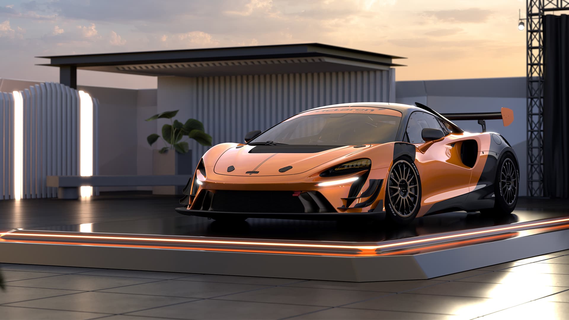 A metallic orange McLaren Artura Trophy Evo, parked on lit up podium, in a modern building with and open roof, at sunset. 