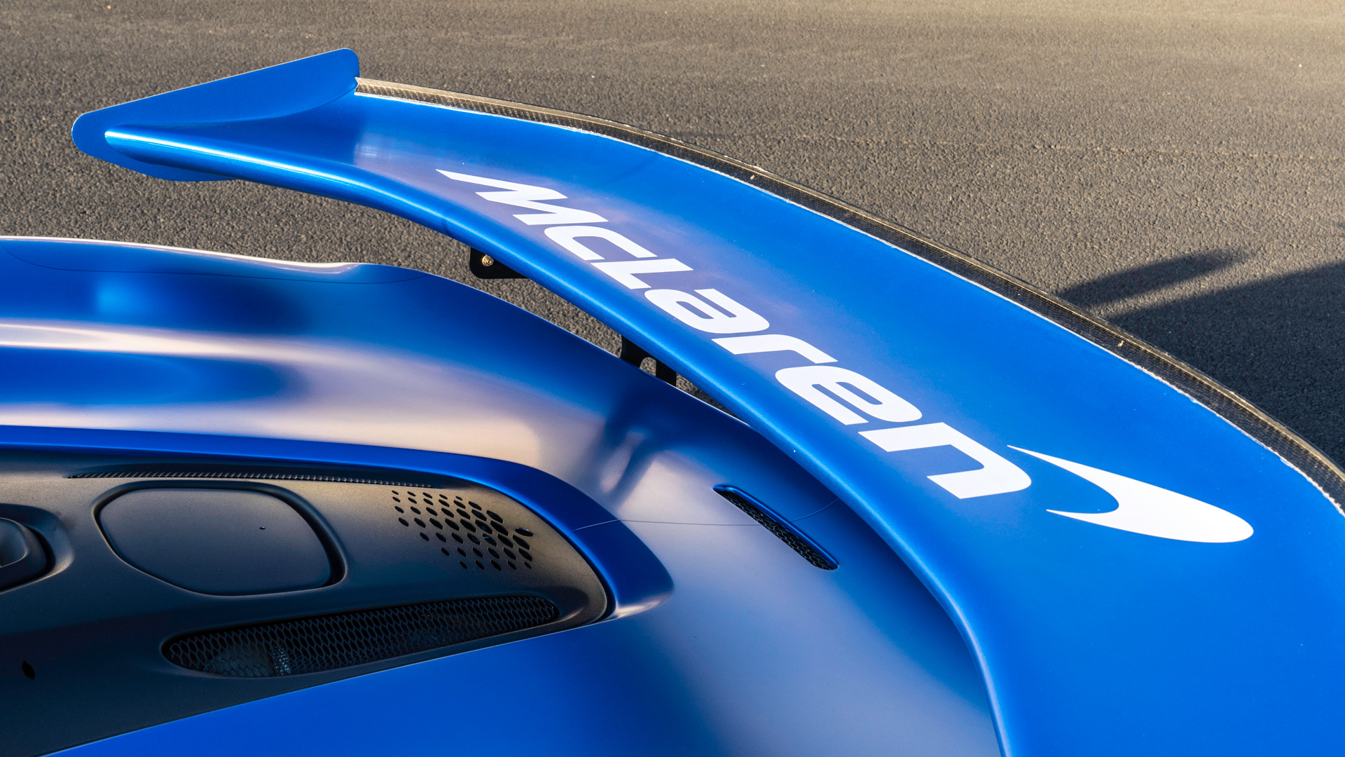 The rear wing of a bright blue McLaren.