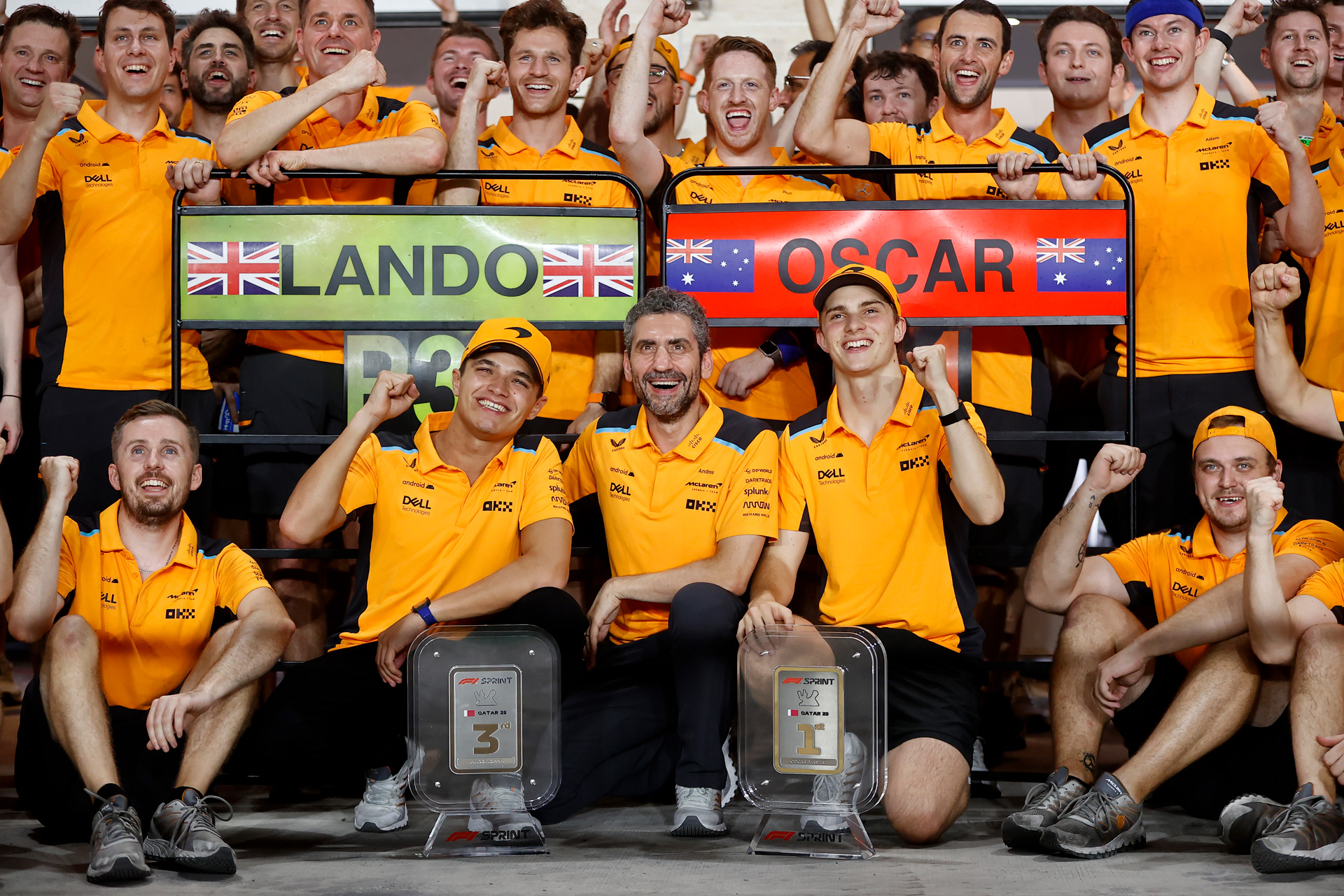 The whole McLaren F1 team posing victoriously with trophies. 