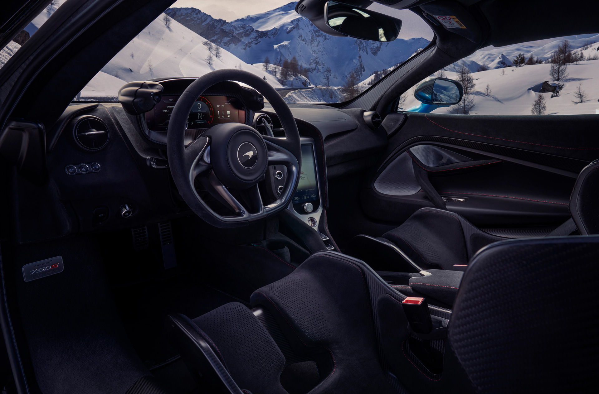 Interior of a McLaren 750S parked in snowy mountains.