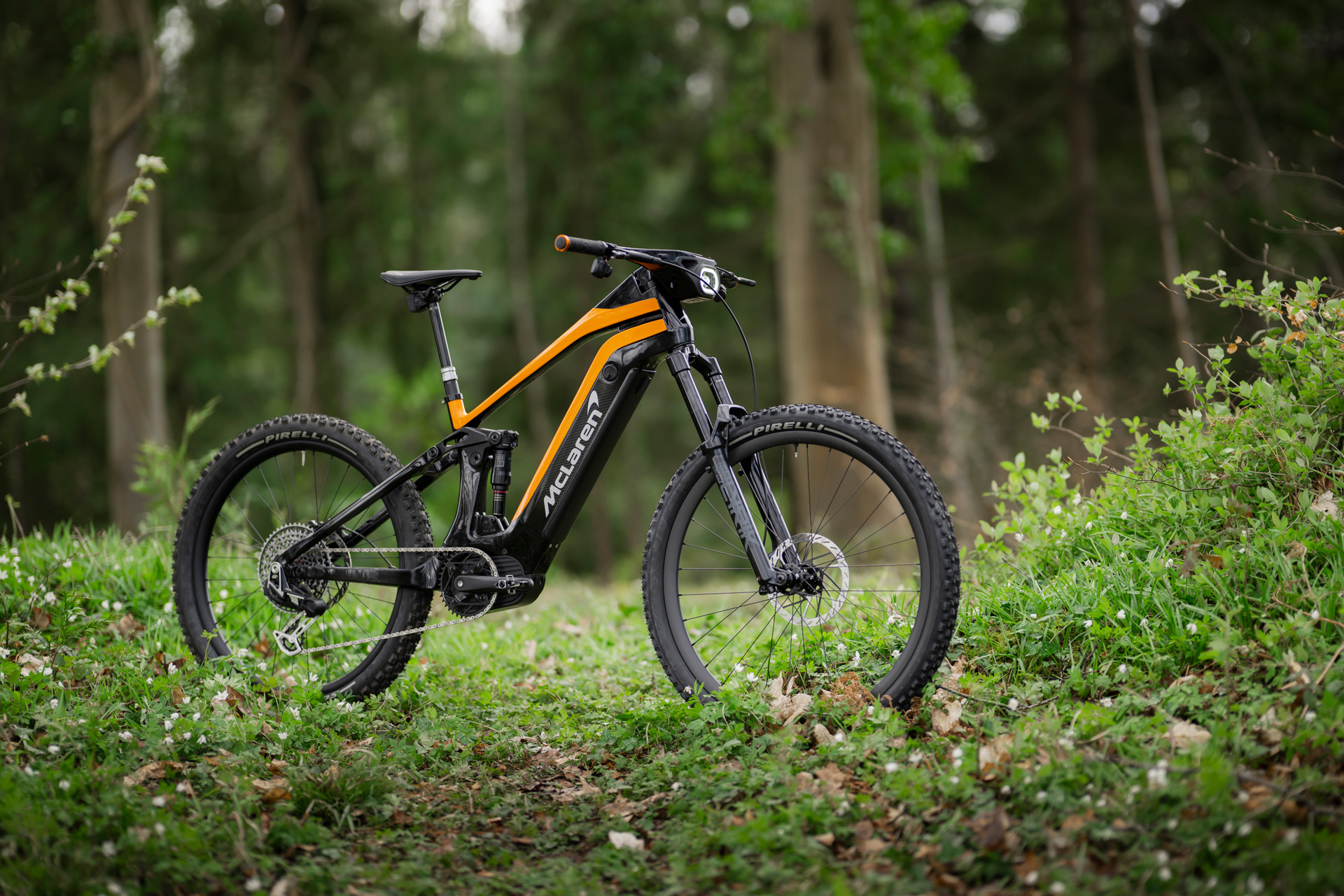 Orange McLaren E-bike Extreme model in a forest. 