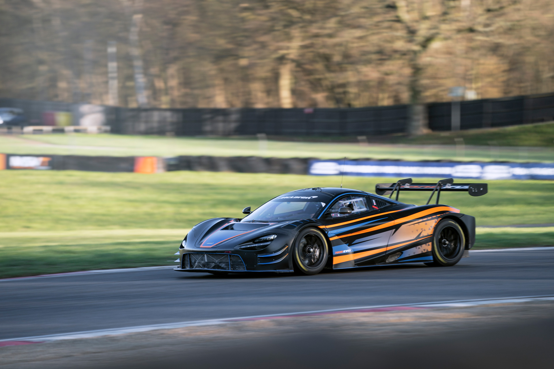 The McLaren 720S GT3 EVO driving around a race track at speed.