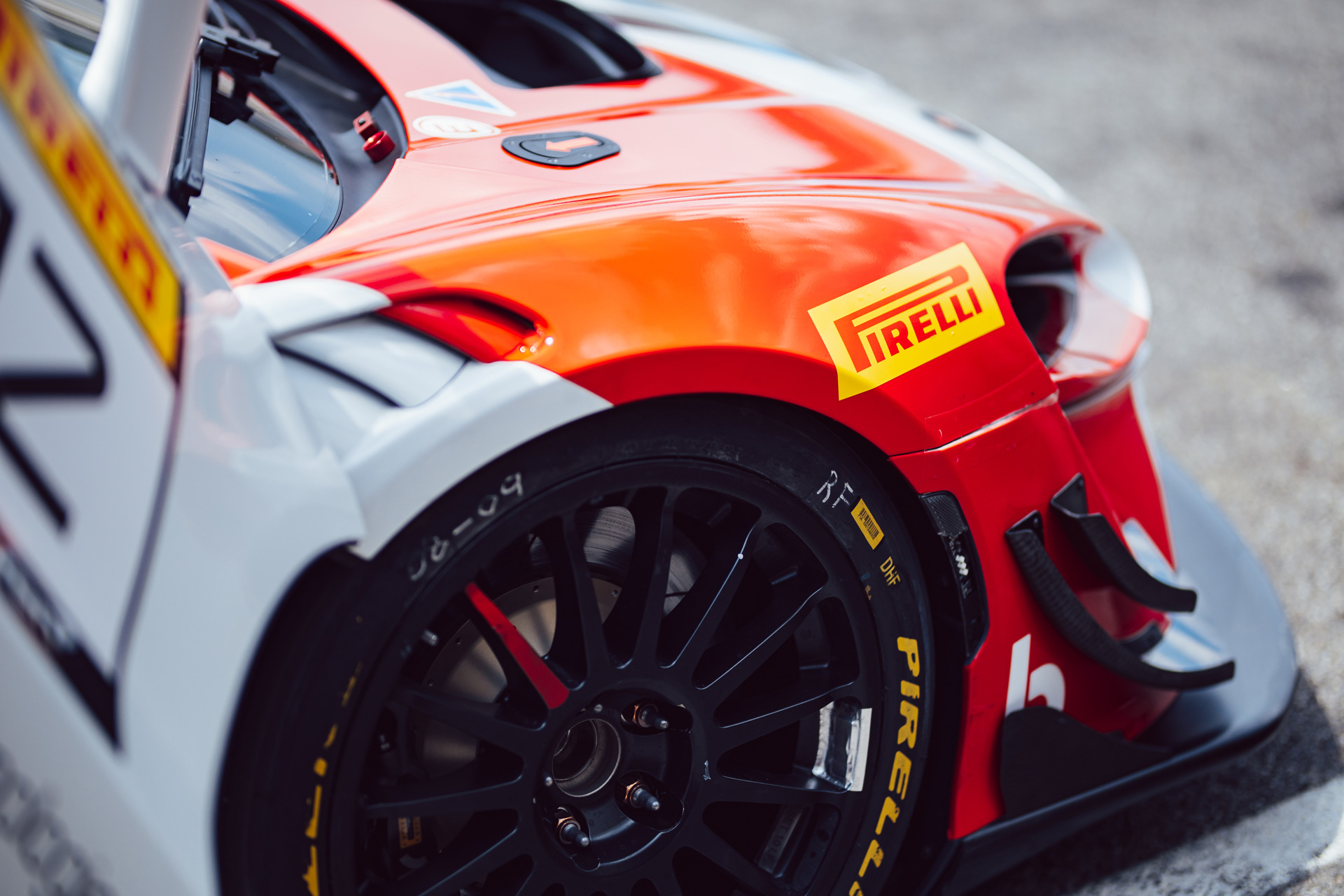 Close up detail of Pirelli tyre and logo on a brightly coloured McLaren car.