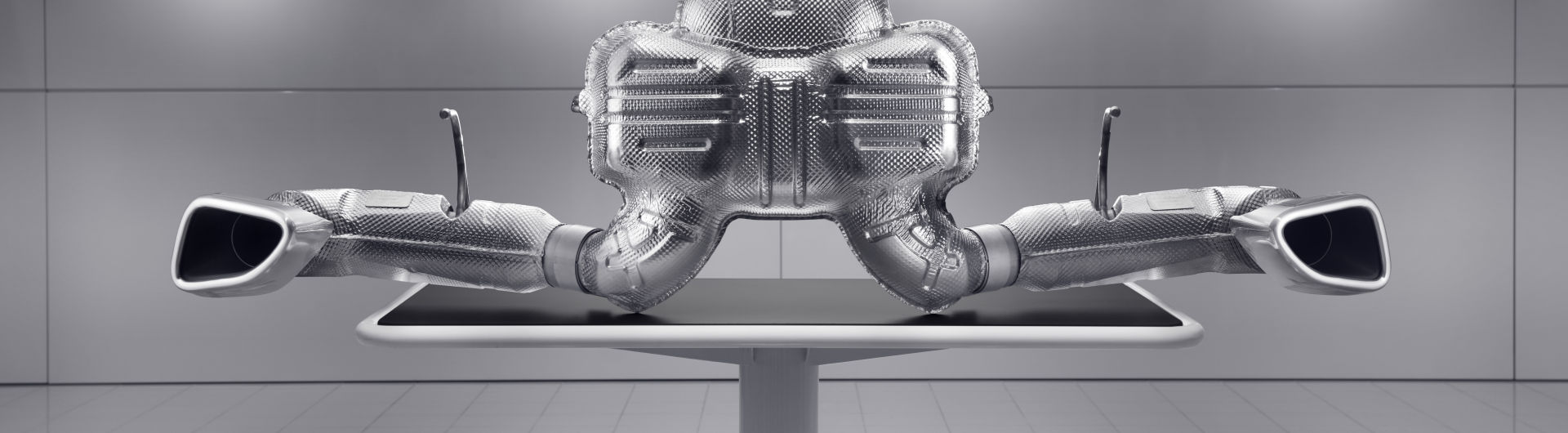 A large, detailed image of a McLaren exhaust system and muffler, on display in a clean, modern setting.