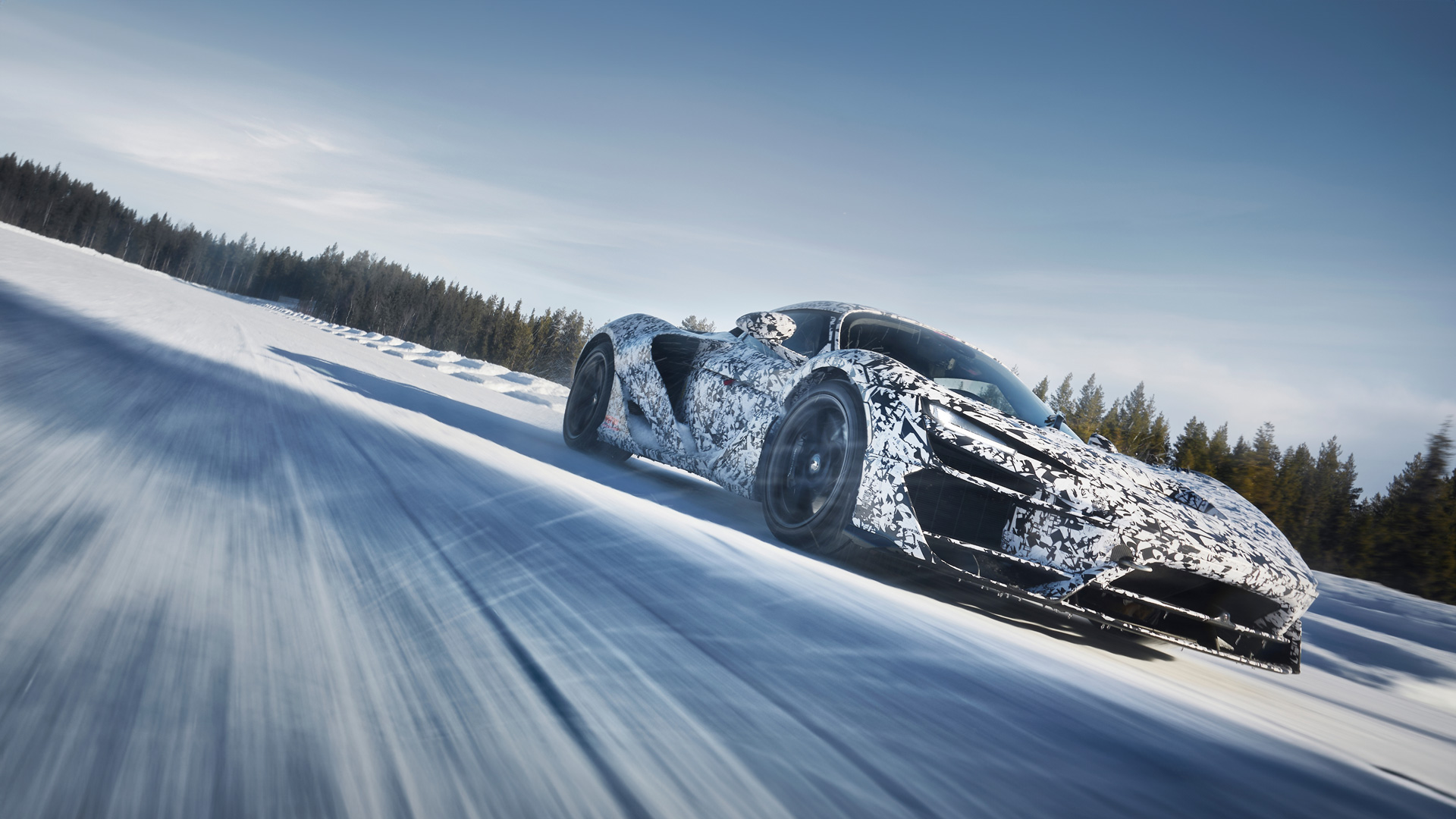 Black and white patterned McLaren W1 driving on a snowy road at speed.